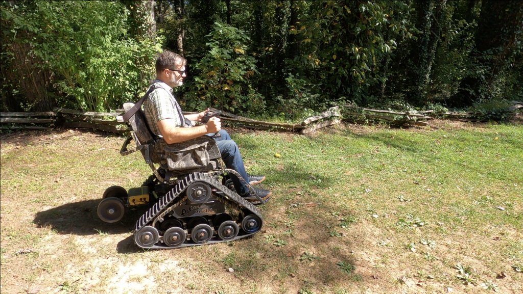 Man uses offroad trackchair on a grassy field